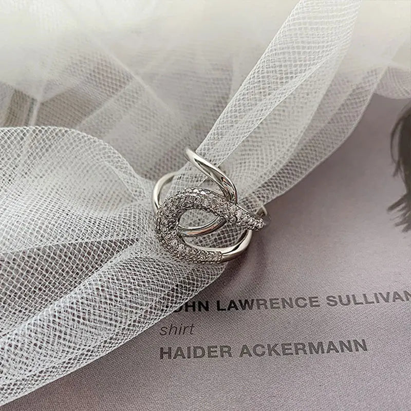 Curved diamond contour wedding band in elegant silver finish, shown on hand with blue matte nails. Stylish gold and white gold ring for special occasions.