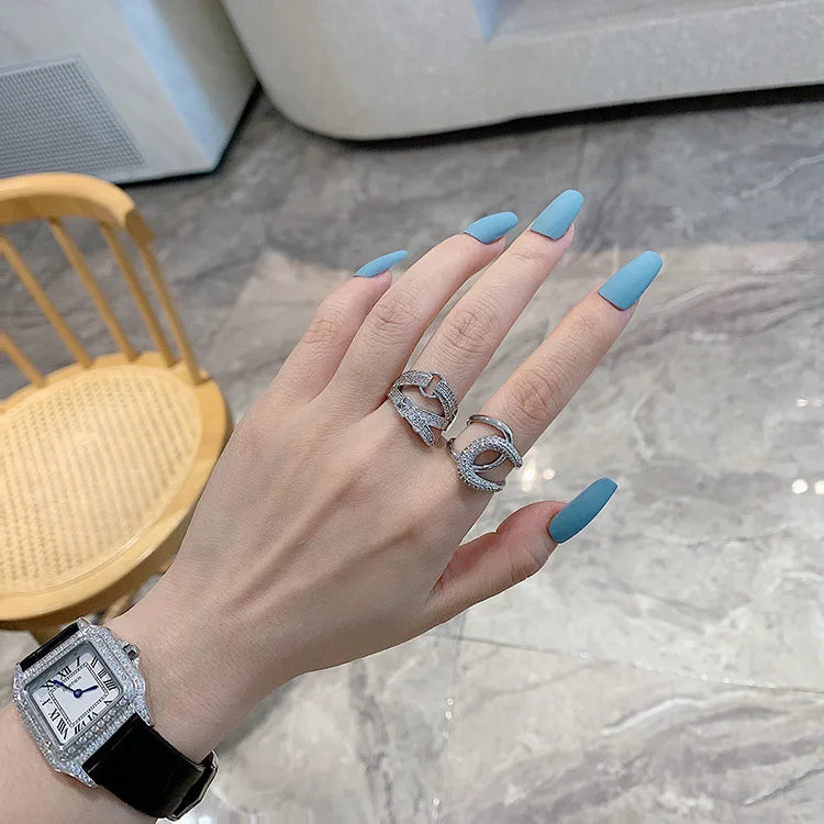 Curved diamond contour wedding band in elegant silver finish, shown on hand with blue matte nails. Stylish gold and white gold ring for special occasions.