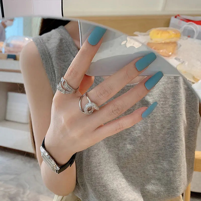 Curved diamond contour wedding band in elegant silver finish, shown on hand with blue matte nails. Stylish gold and white gold ring for special occasions.