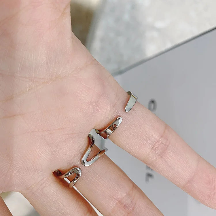 Curved diamond contour wedding band in elegant silver finish, shown on hand with blue matte nails. Stylish gold and white gold ring for special occasions.