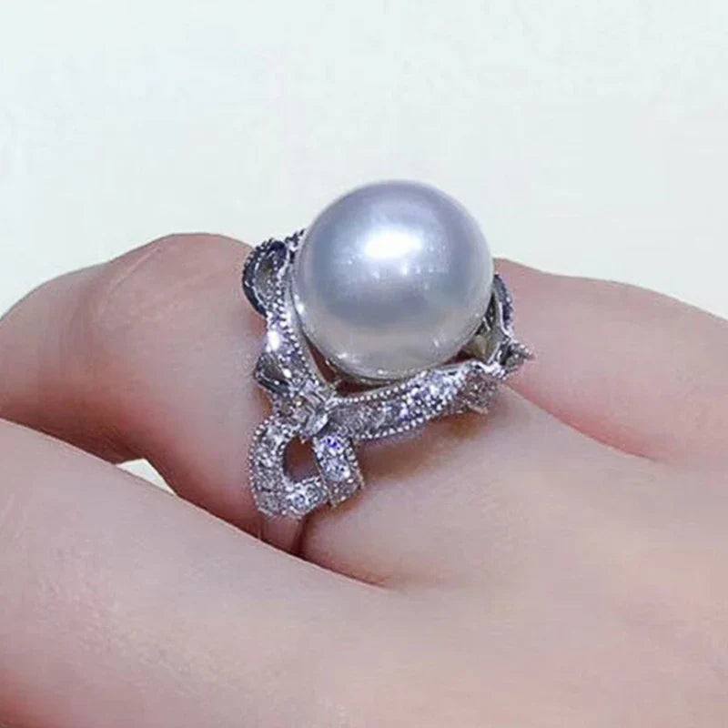 Huitan romantic bridal ring for women featuring a large pearl centerpiece and elegant twisted band with sparkling pavé stones, ideal for weddings.
