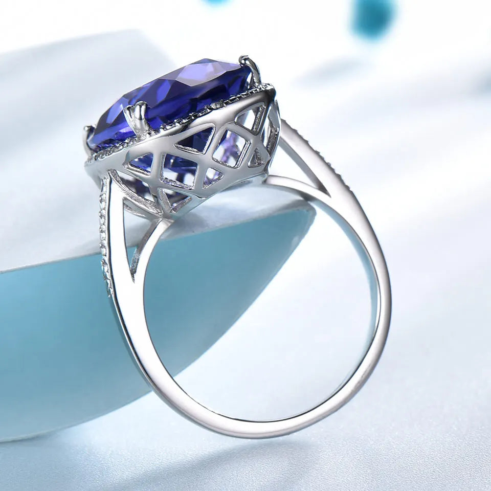 Elegant Silver Wedding Ring with round-cut Tanzanite Zircon on hand, showcasing fine jewelry craftsmanship for engagements or weddings.