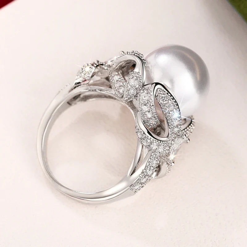 Huitan romantic bridal ring for women featuring a large pearl centerpiece and elegant twisted band with sparkling pavé stones, ideal for weddings.