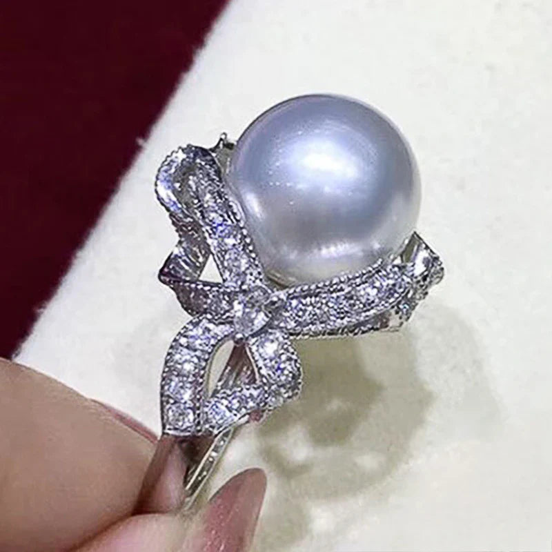 Huitan romantic bridal ring for women featuring a large pearl centerpiece and elegant twisted band with sparkling pavé stones, ideal for weddings.