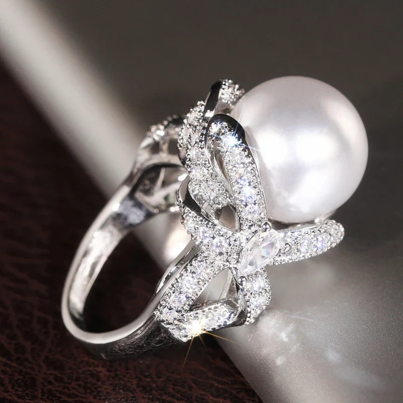 Huitan romantic bridal ring for women featuring a large pearl centerpiece and elegant twisted band with sparkling pavé stones, ideal for weddings.